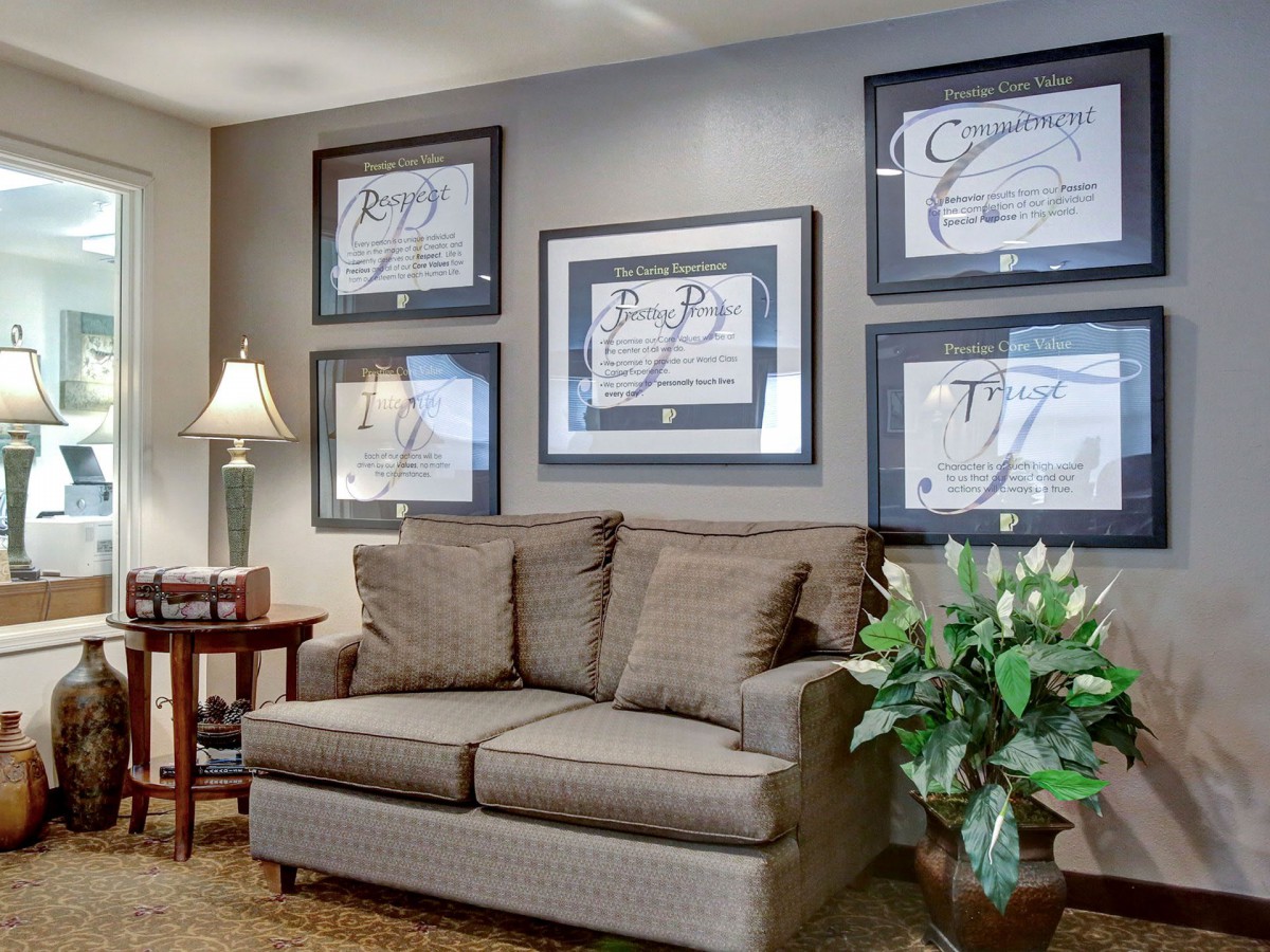 A cozy living room with a sofa, decorative art on the wall, and a side table with a lamp.