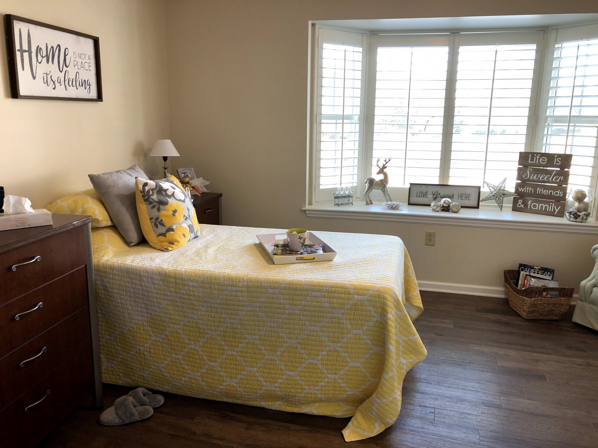 A cozy bedroom with yellow bedding, showcasing a single bed and a window seat adorned with various decorations.