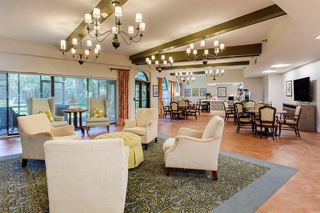 A spacious and elegantly decorated lounge area with chandeliers and comfortable seating.