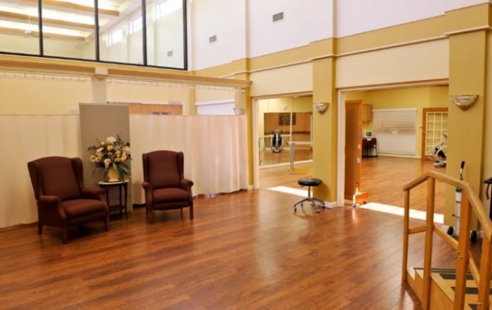 A spacious dance studio with hardwood floors, mirrors, and comfortable seating.