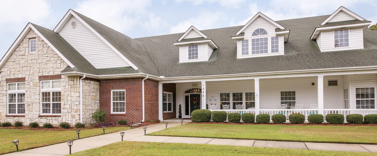 A beautiful suburban home with a spacious front porch and well-maintained lawn.
