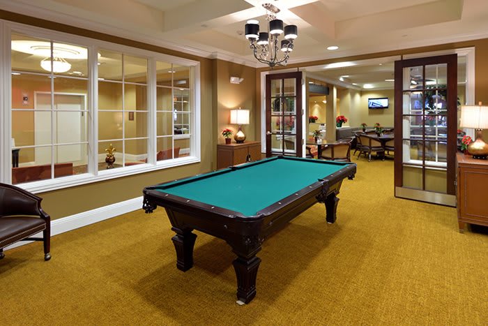 A well-furnished game room featuring a pool table under elegant lighting.