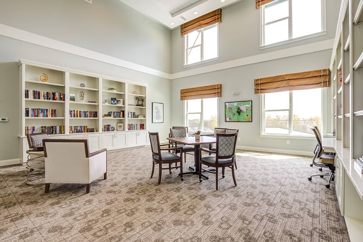 A spacious library room with large windows and elegant furnishings.