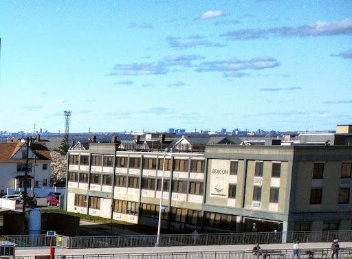 A view of a modern building set against a clear blue sky with scattered clouds.