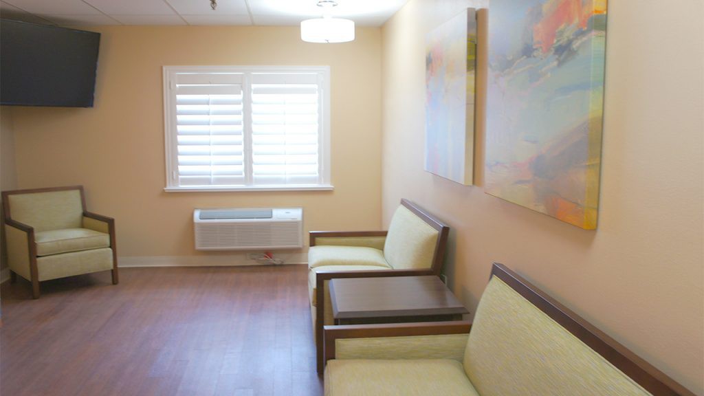 A simple waiting room with chairs and artwork on the wall.