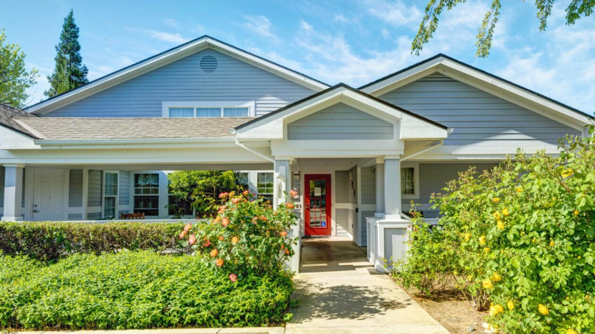 A charming residential house with a red door and landscaped garden.
