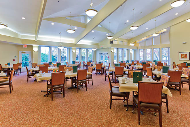 Spacious dining area with neatly arranged tables and chairs, enhanced by natural light from large windows.