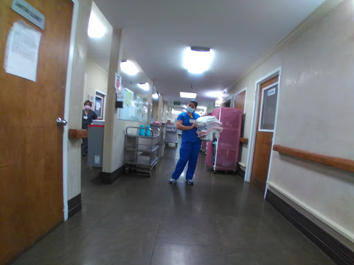 A nurse in scrubs navigates through a hospital corridor, carrying supplies.