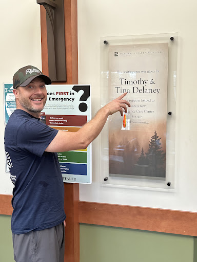 A man smiling and pointing at a poster indoors.