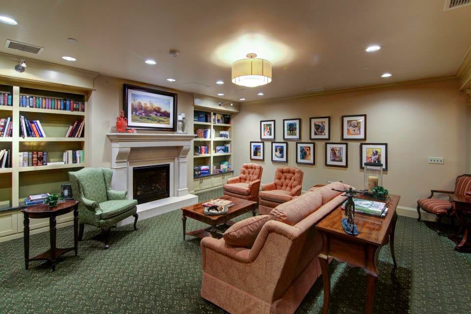 A cozy living room featuring a fireplace, artwork on the walls, and comfortable seating arrangements.
