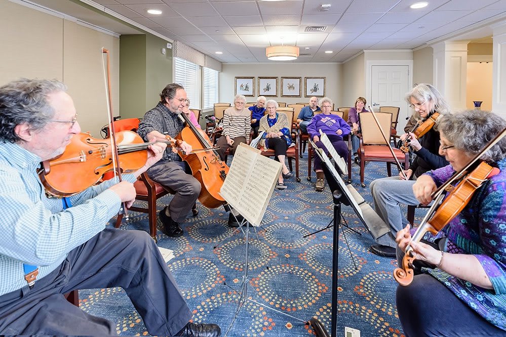 A group of musicians rehearsing indoors with string instruments.