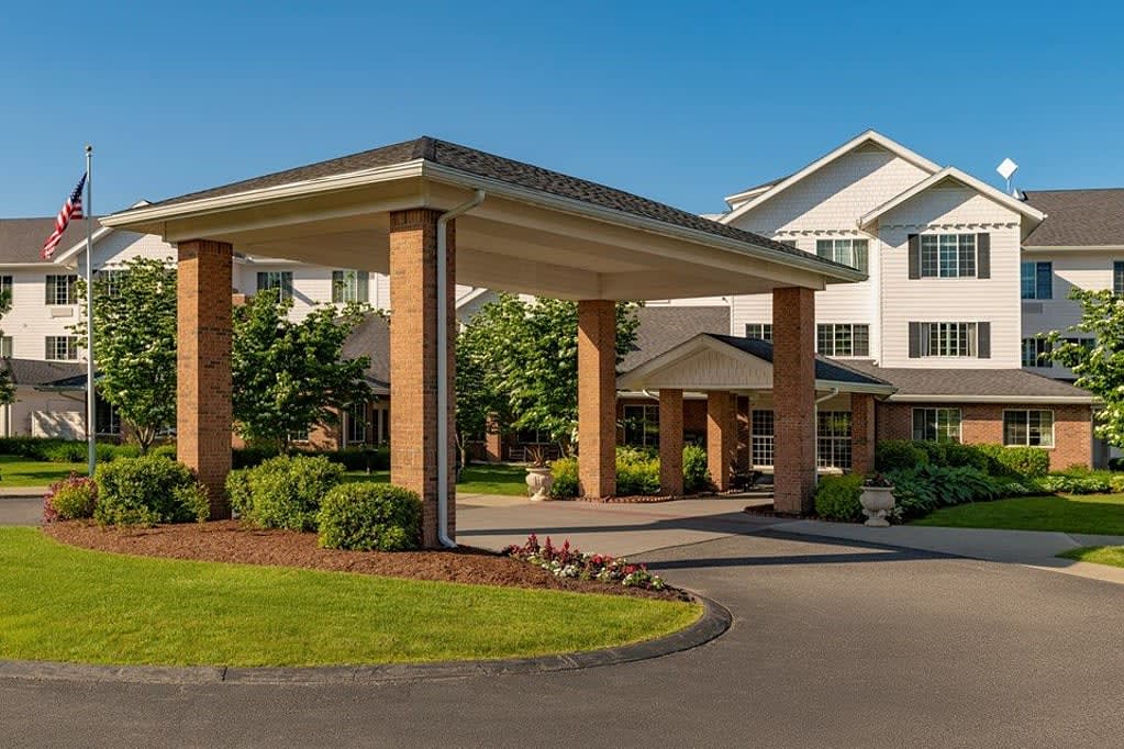 A welcoming building entrance with well-maintained landscaping and a covered driveway.