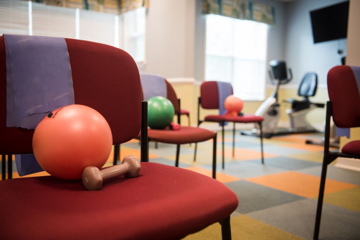 A fitness room with chairs, medicine balls, and dumbbells arranged for a workout session.