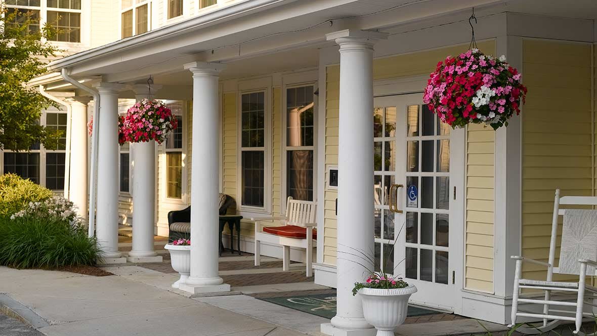 A welcoming porch with white columns and hanging flower baskets.
