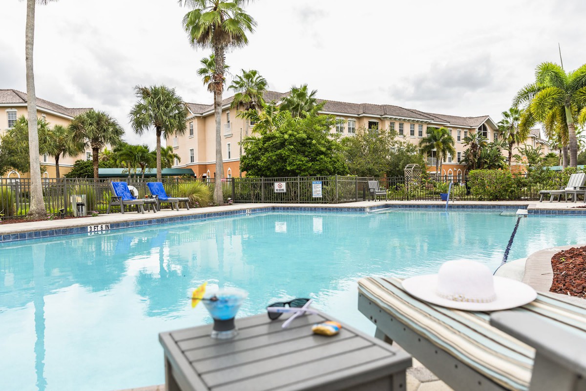 A relaxing outdoor pool area at a resort, surrounded by palm trees and lounge chairs.