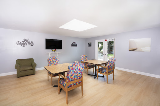 A bright and inviting living space featuring colorful chairs and a television, perfect for leisure and social gatherings.