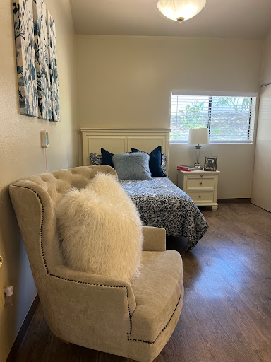 A cozy bedroom featuring a comfortable bed, stylish armchair, and natural light from the window.