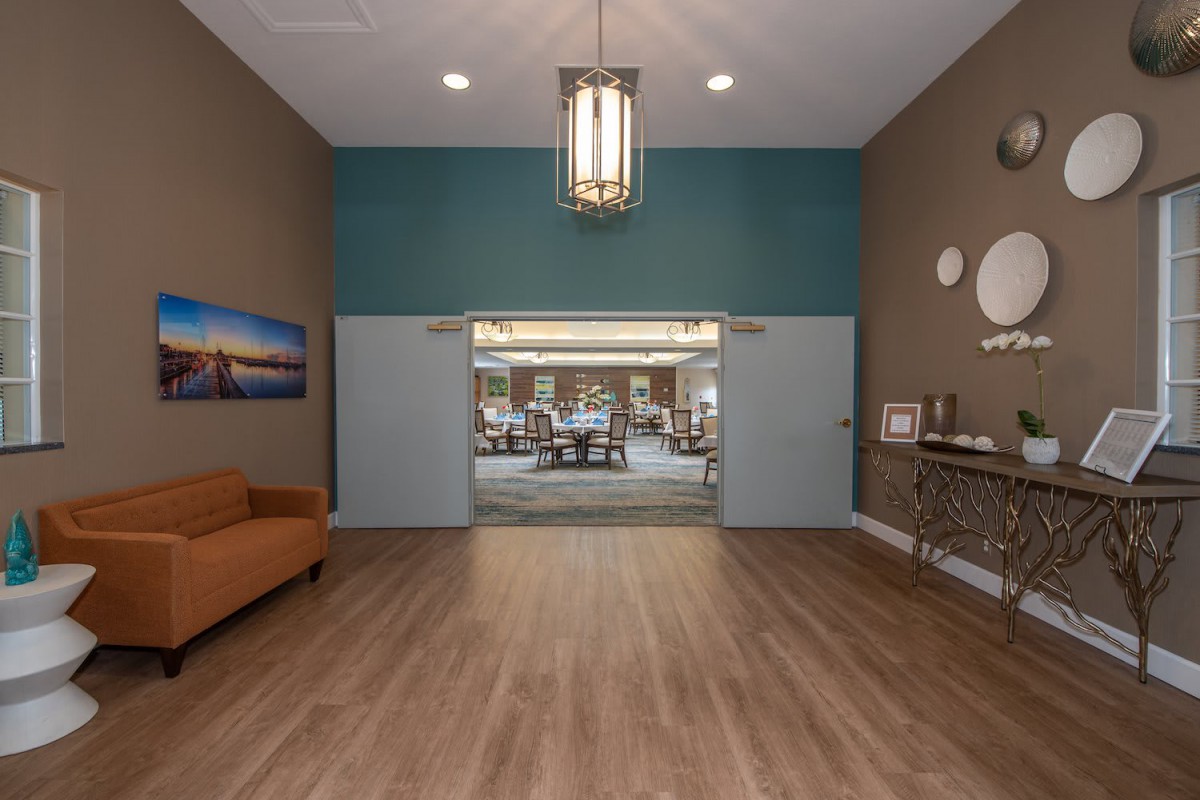 A modern lobby with wooden flooring, a chandelier, and comfortable seating.