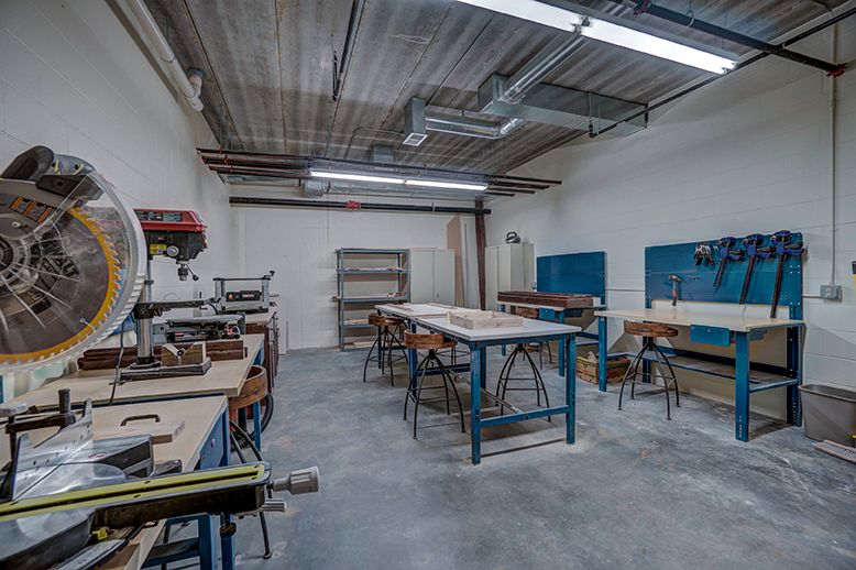 An industrial workshop with workbenches and various tools arranged for woodworking.