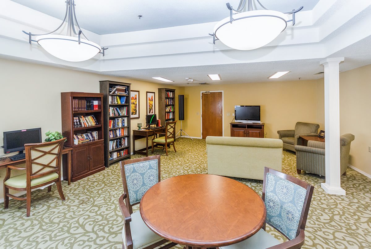 A cozy library area with bookshelves, seating, and a computer station.