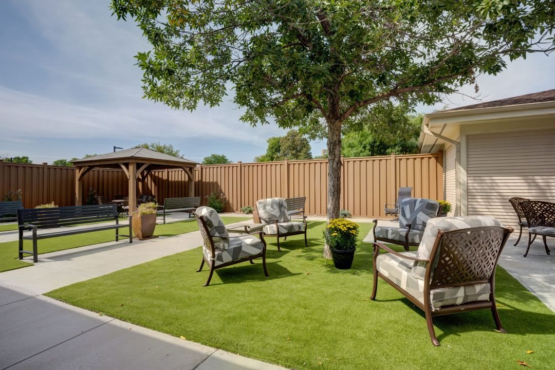 A serene backyard patio area with comfortable seating under a tree.