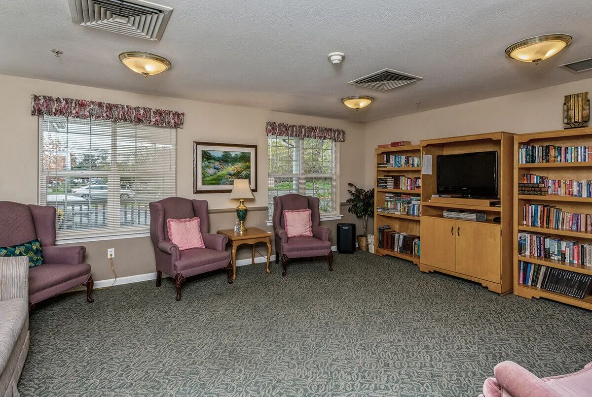 A cozy living room with armchairs, a television, and a bookshelf.