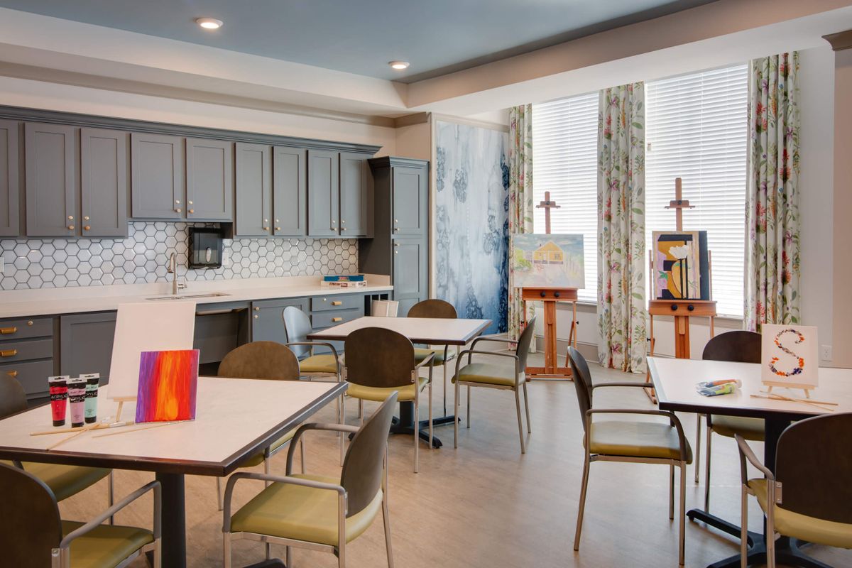 A modern kitchen and dining area with several tables and chairs, featuring contemporary decor and ample lighting.