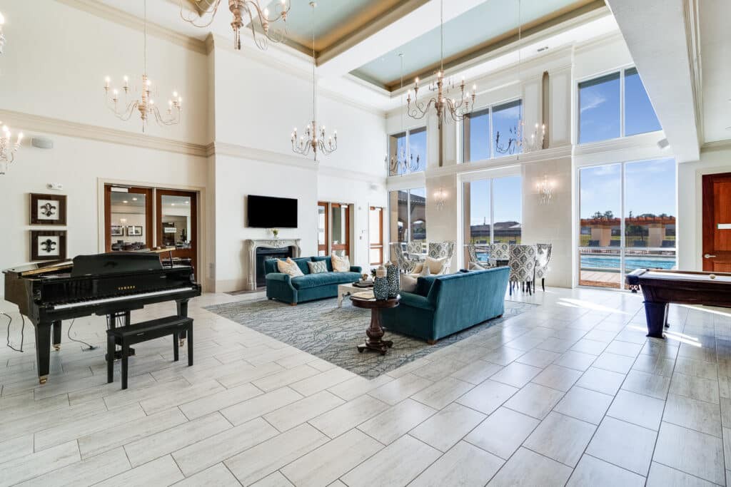 A luxurious living room with high ceilings, chandeliers, and large windows overlooking a scenic view.