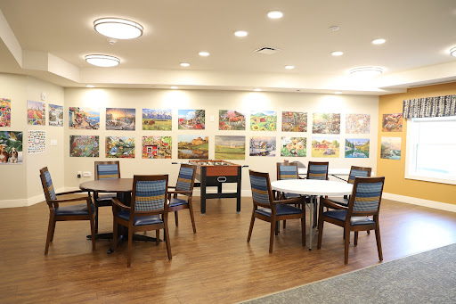 A cozy dining area featuring several tables and chairs, adorned with vibrant artwork on the walls.