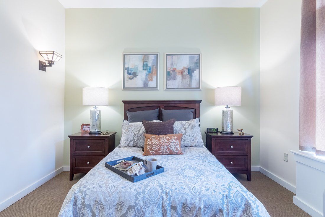 A well-decorated bedroom with matching nightstands and lamps, featuring a neatly made bed with a decorative tray.