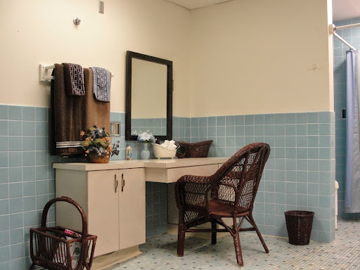 A cozy bathroom vanity setup featuring a mirror, chair, and neatly arranged towels.