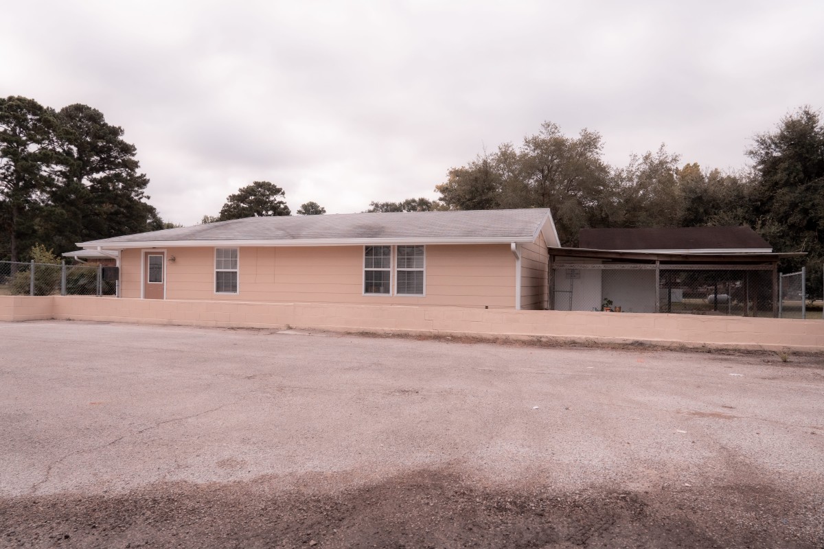 A single-story house with a driveway and cloudy sky.