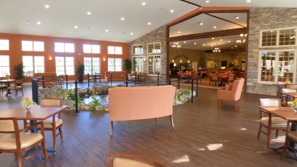 A spacious and well-lit lounge area with comfortable seating, large windows, and indoor plants.