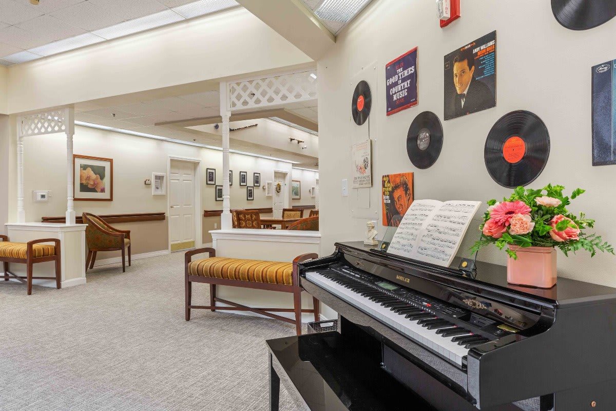 A cozy music room featuring a piano with sheet music, surrounded by vintage records on the walls.