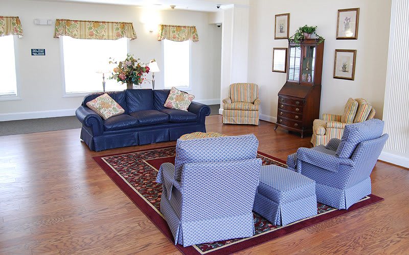 A cozy living room with blue sofas, armchairs, and a patterned rug.