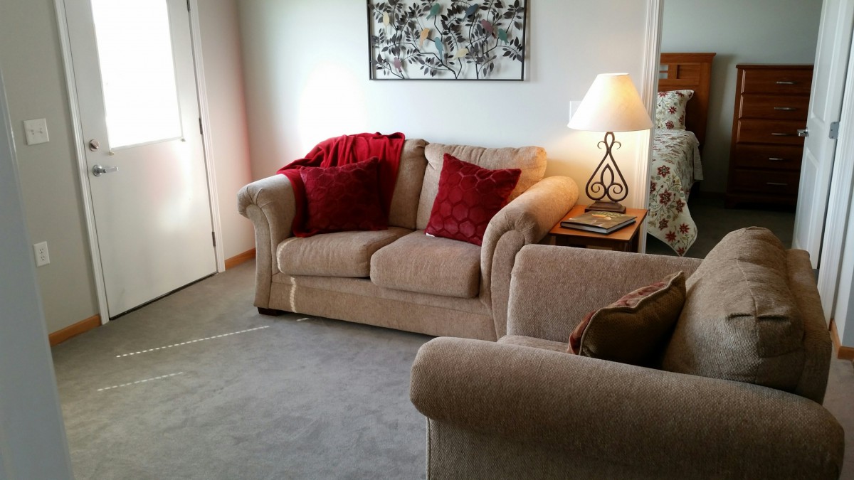 A cozy living room with a beige sofa, red cushions, and a decorative lamp.