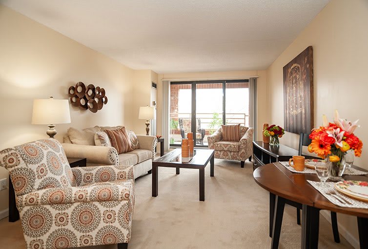 A cozy living room with comfortable seating, decorative accents, and a view of the balcony.