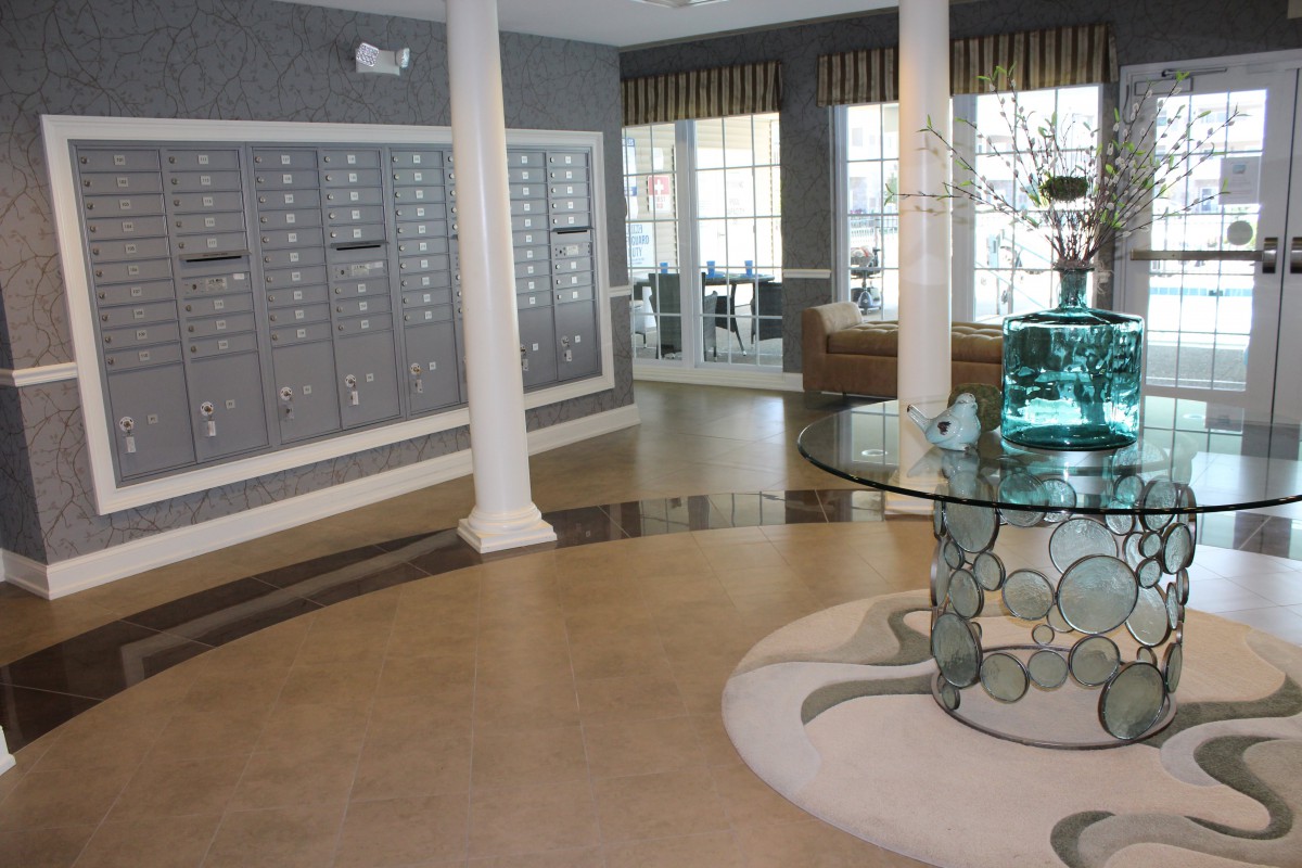 A neatly organized apartment lobby mailroom featuring multiple mailboxes and a decorative glass table.