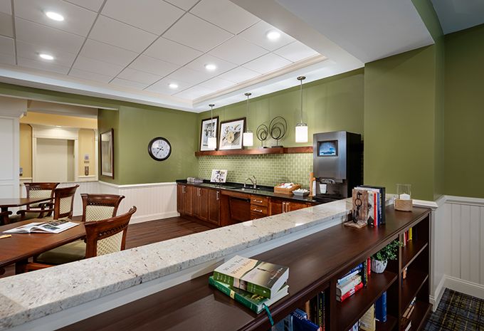 A cozy office lounge area featuring a coffee station and a bookshelf.