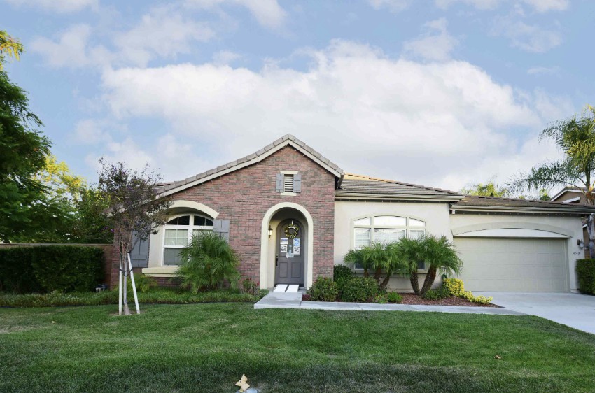 A single-story suburban house with a brick facade and a well-maintained lawn.