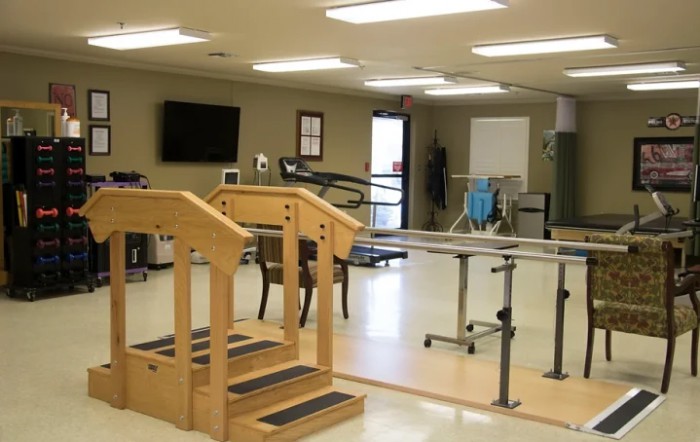 A physical therapy room equipped with parallel bars and a small staircase for rehabilitation exercises.