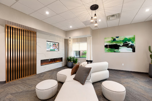 A modern lounge area featuring minimalist furniture and green accents, designed for relaxation.
