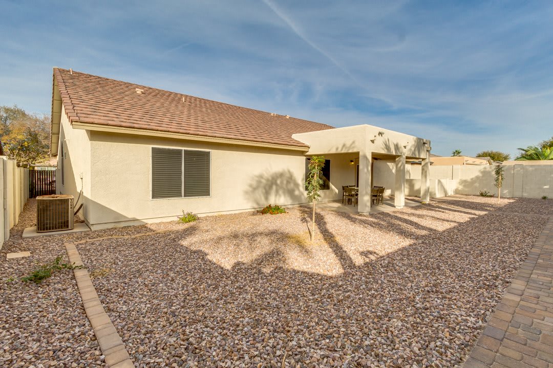 A desert-style backyard with a xeriscaped landscape and covered patio.