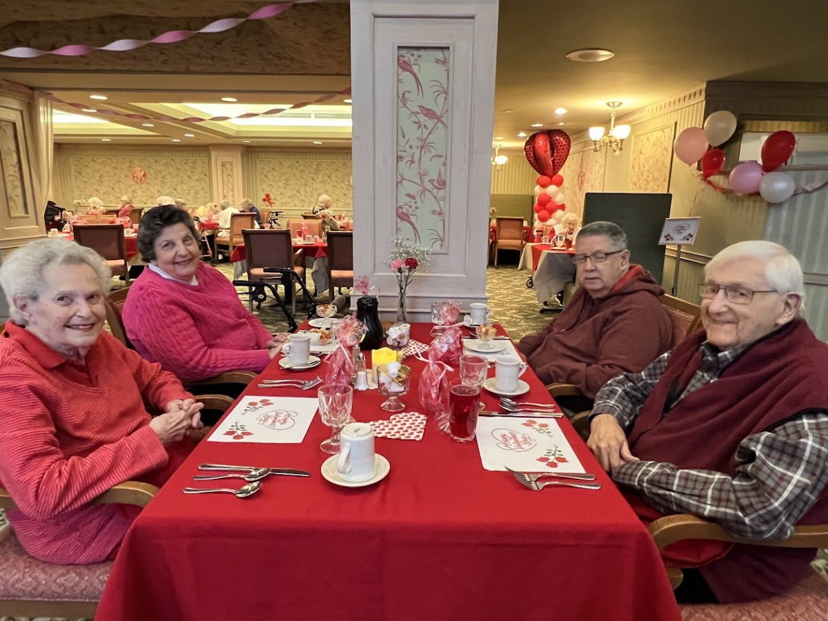 A group of people enjoying a meal at a beautifully decorated table with red themed decor in an indoor setting.