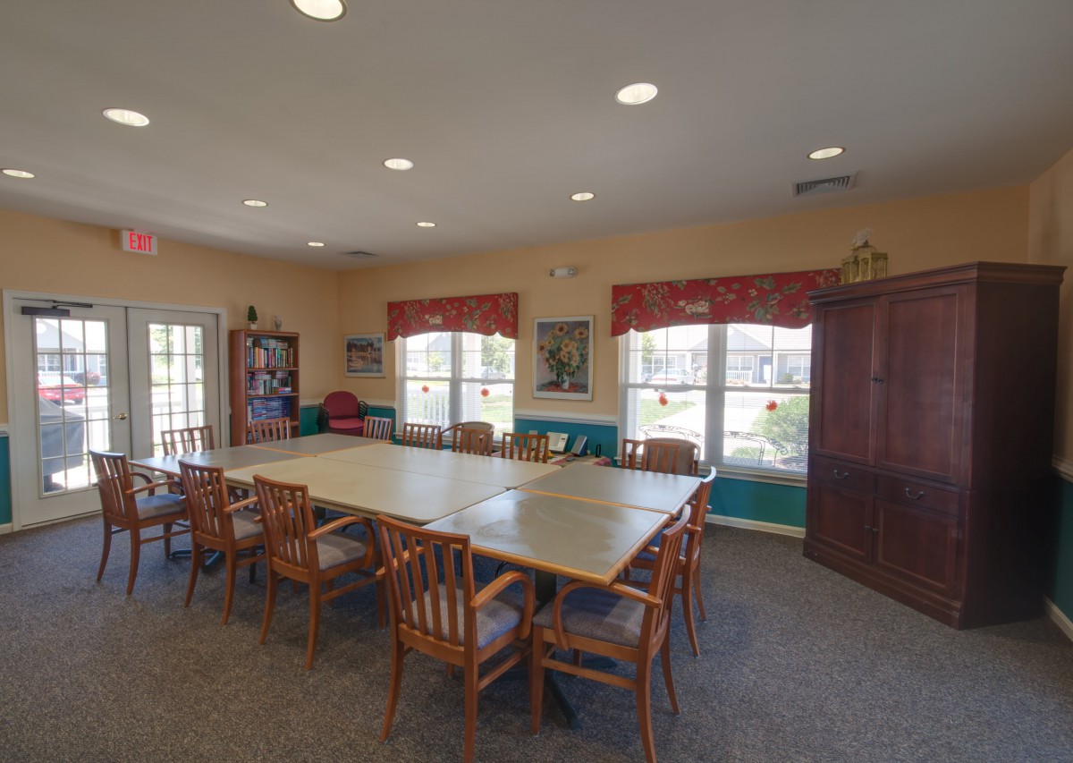 A spacious conference room with a large table and wooden chairs, featuring natural light from multiple windows.