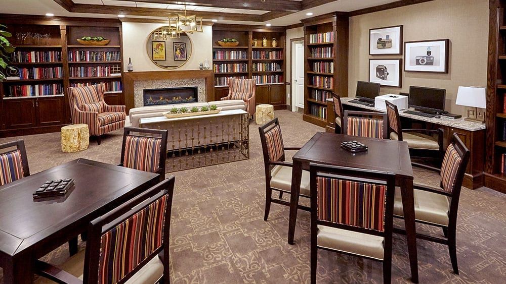 Cozy library interior with bookshelves, a fireplace, and seating areas.