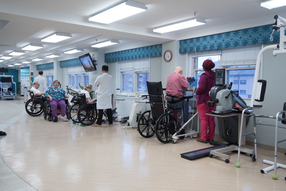 A rehabilitation center where patients are receiving physical therapy with the assistance of medical staff.