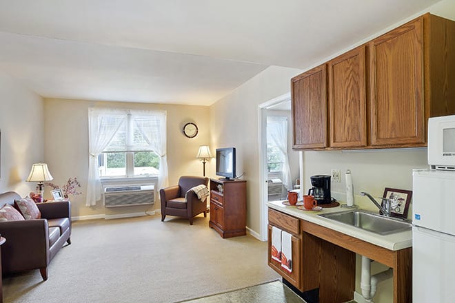 A cozy apartment living space featuring a kitchenette and a sitting area with natural light.