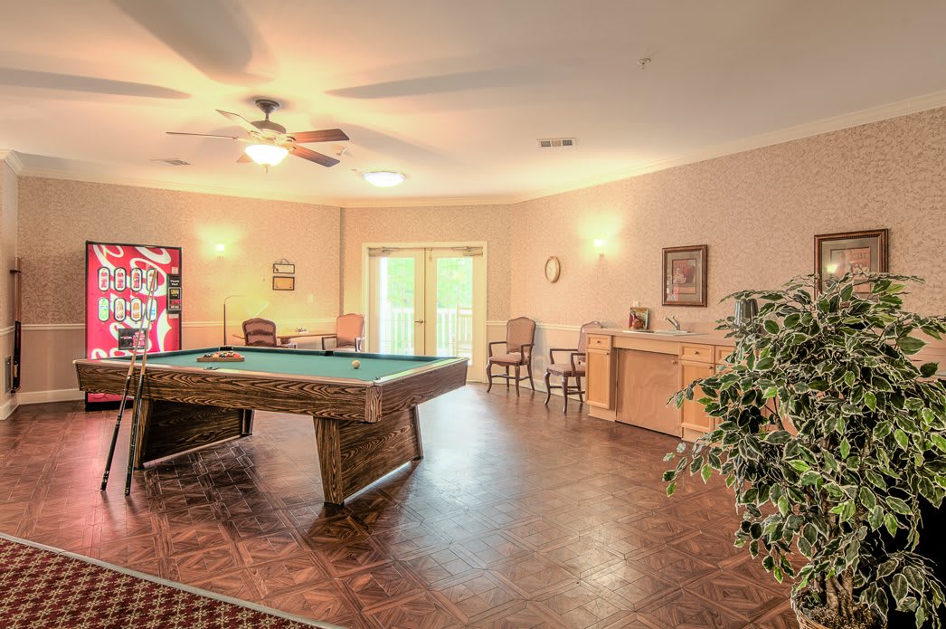 A spacious game room featuring a pool table with overhead lighting and a ceiling fan, providing a comfortable atmosphere for leisure activities.