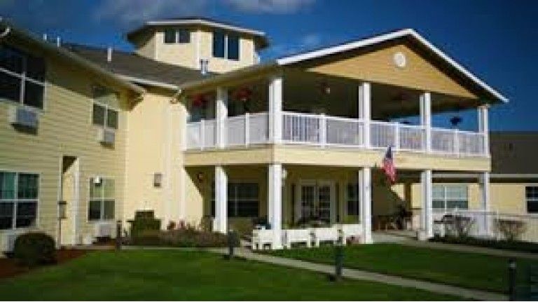A two-story suburban house with a large porch and well-maintained lawn.